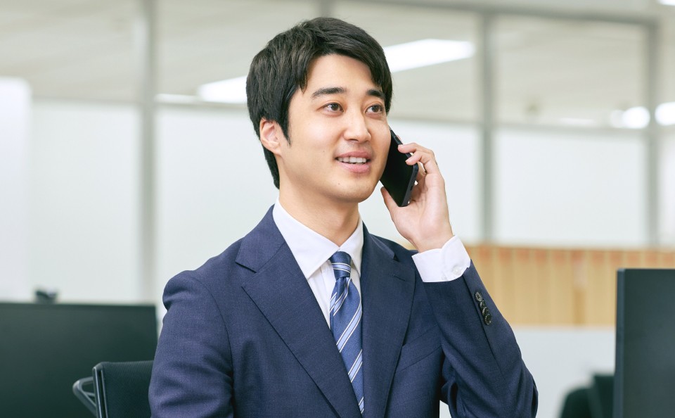 スマートフォンを持って電話している営業職の男性。