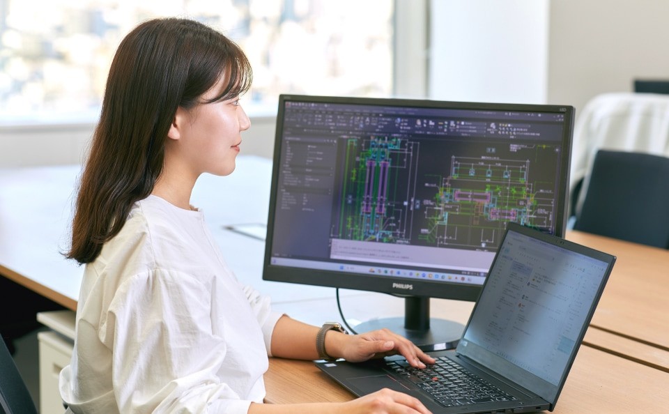 デスクに座りpcで仕事をする設計職の女性。